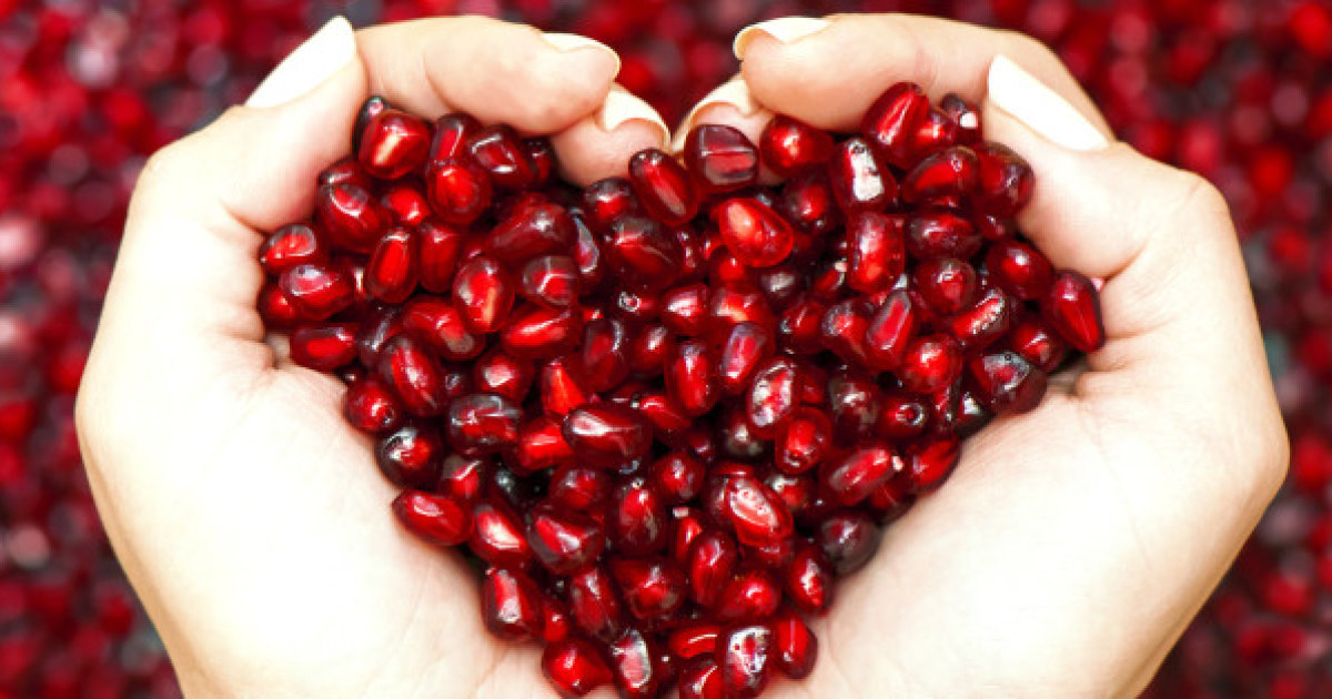 Pomegranate seeds shaping heart in hands